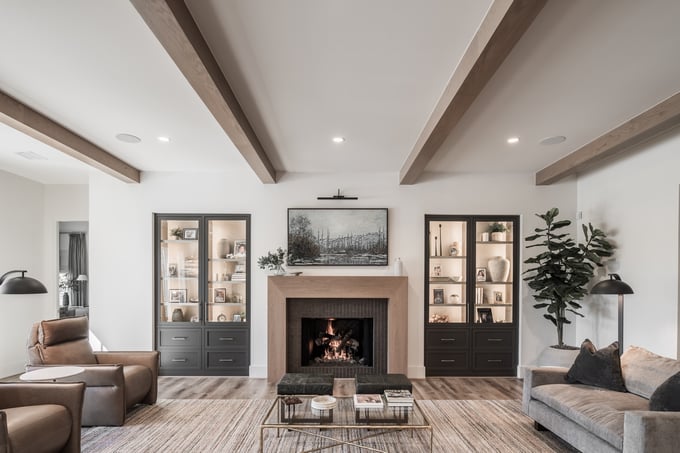 Open living room with exposed ceiling beams, built-in cabinetry, fireplace focal point, and a symmetrical layout designed for scale and comfort.