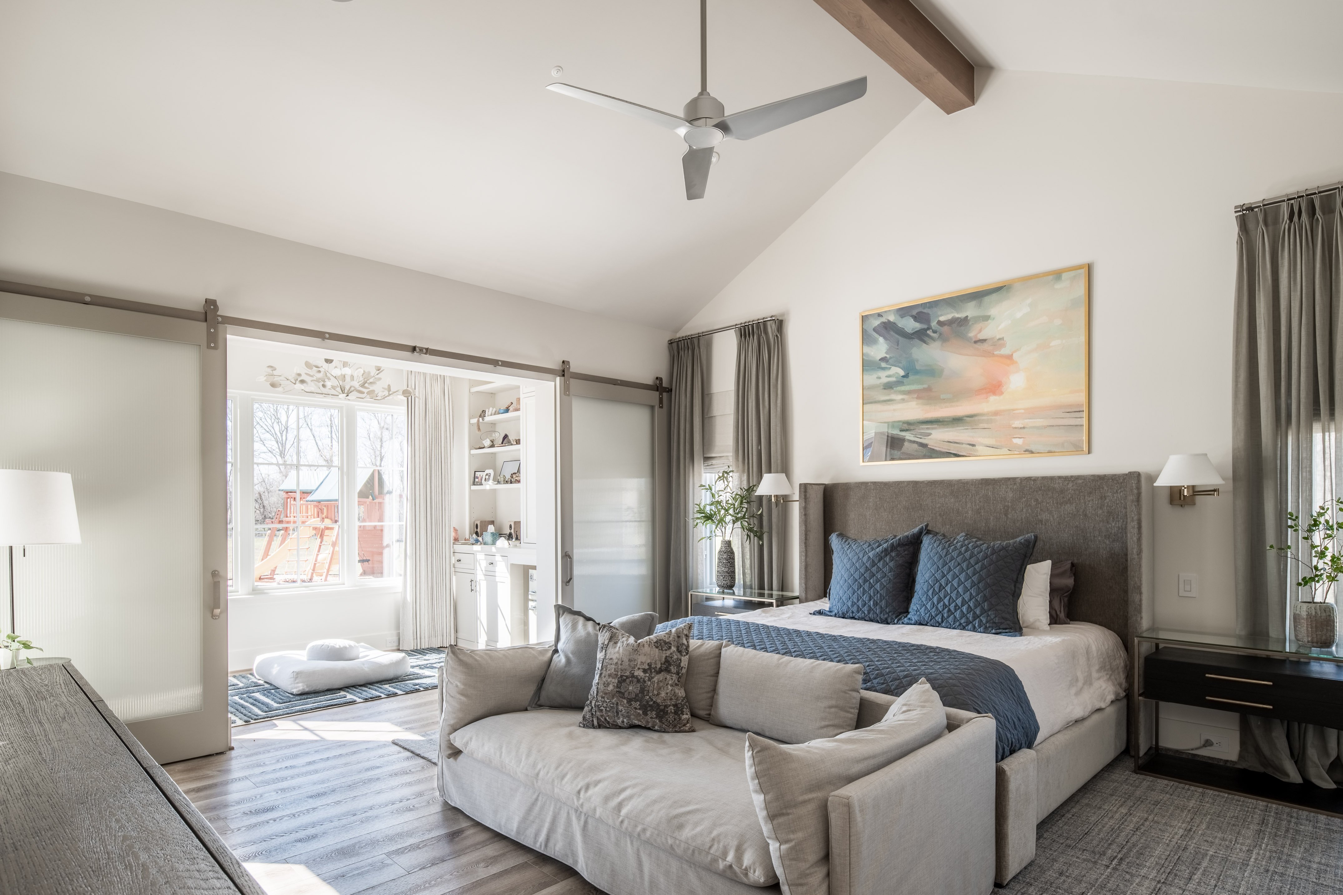 Primary bedroom with vaulted ceiling, sliding barn doors, soft neutral finishes, and a layout that prioritizes comfort and efficient use of space.