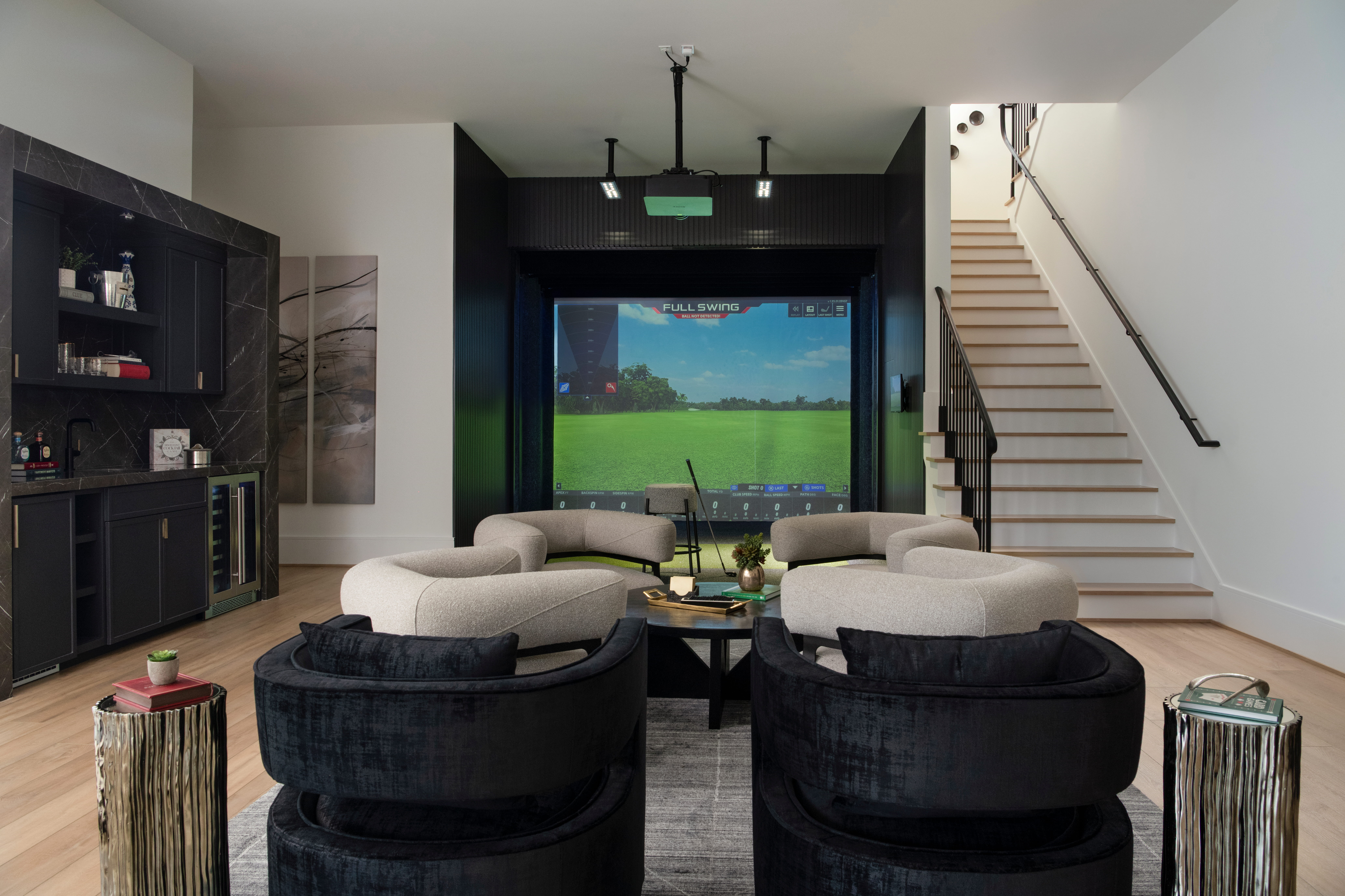 Multi-purpose custom home recreation room with golf simulator, lounge seating, and built-in bar