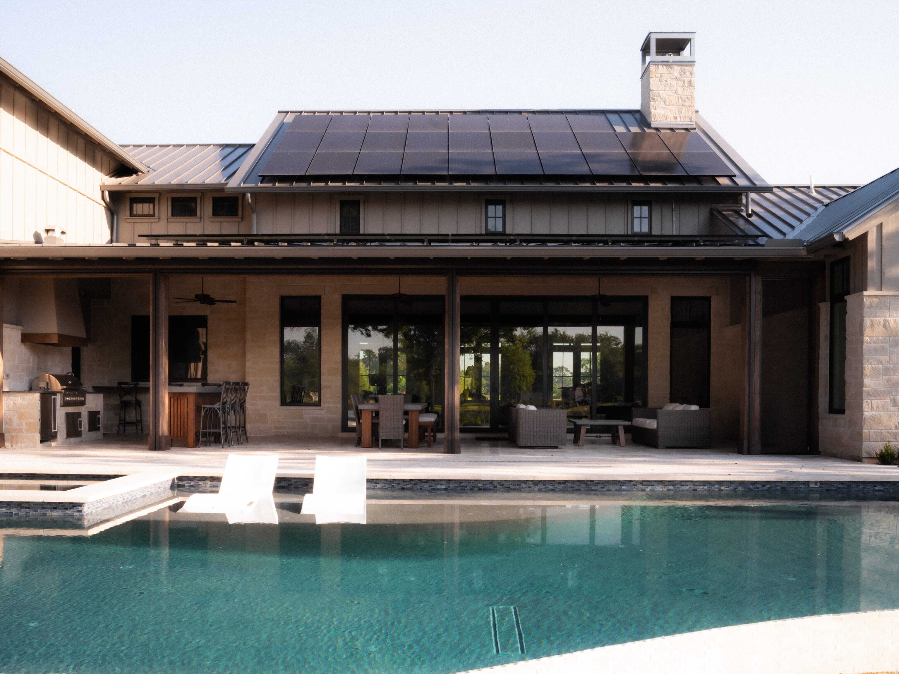 Solar panels on a custom home with covered outdoor living space and backyard pool