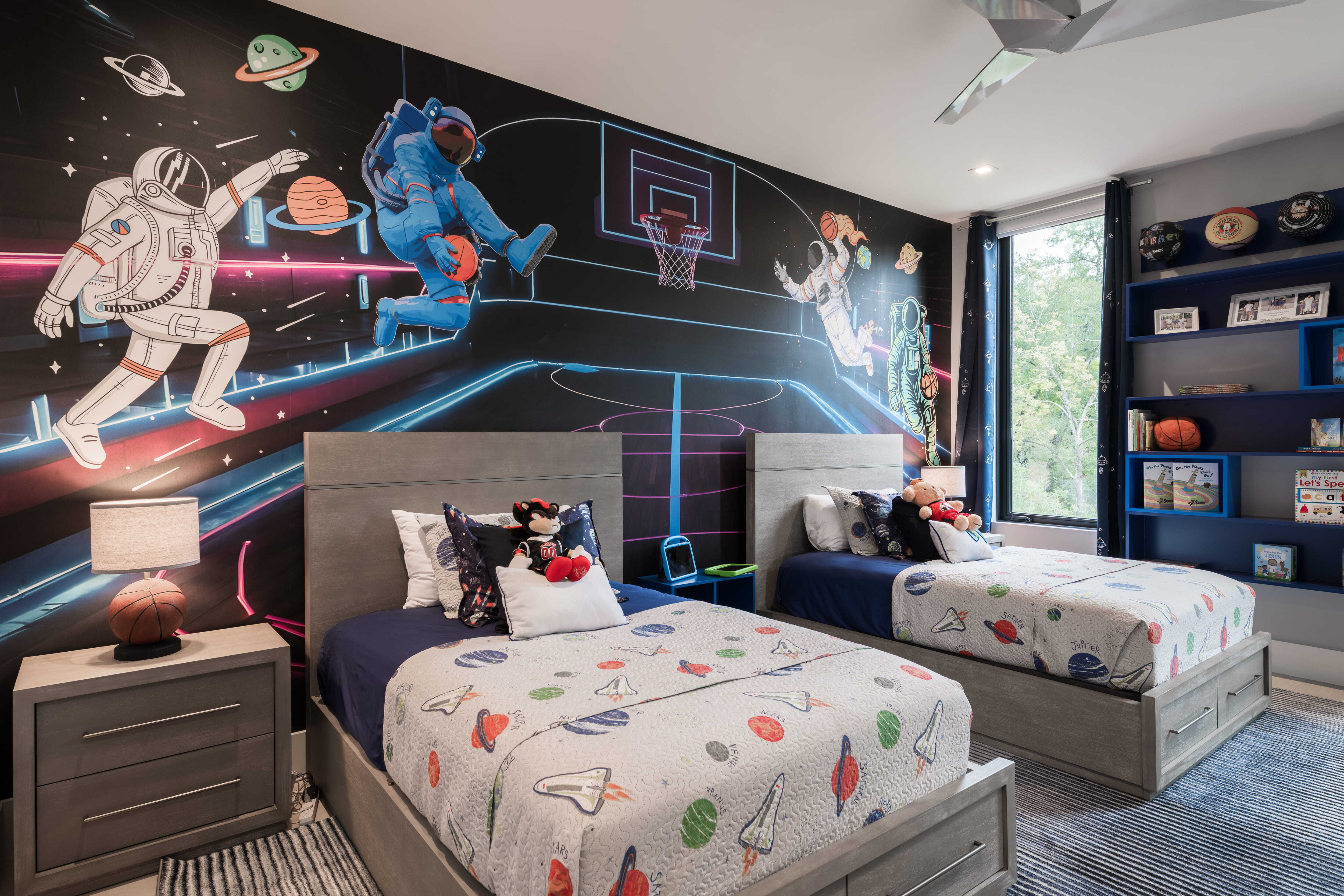 Personalized children’s bedroom with twin beds, space-themed mural, and built-in storage