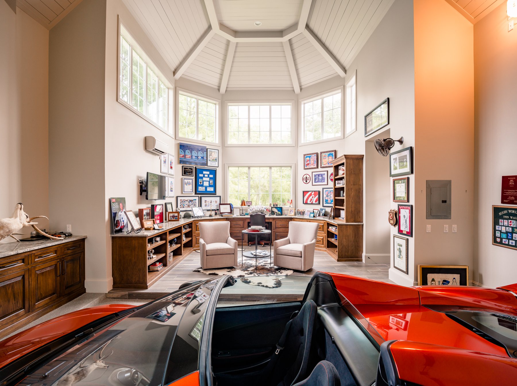 Custom home garage and office with built-in cabinetry, vaulted ceiling, expansive windows, and collector car display.