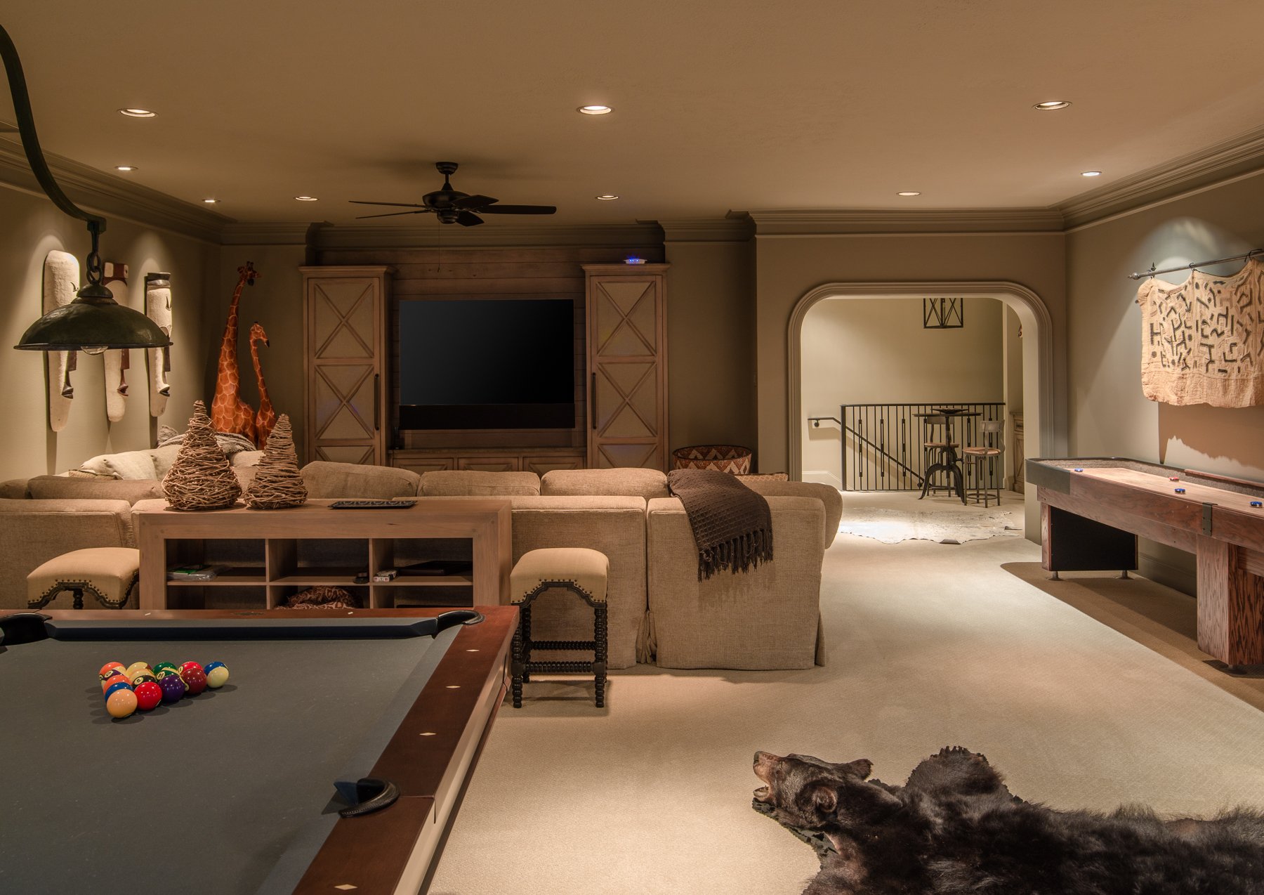 Luxury home game and media room with custom built-ins, pool table, shuffleboard, and layered lighting.