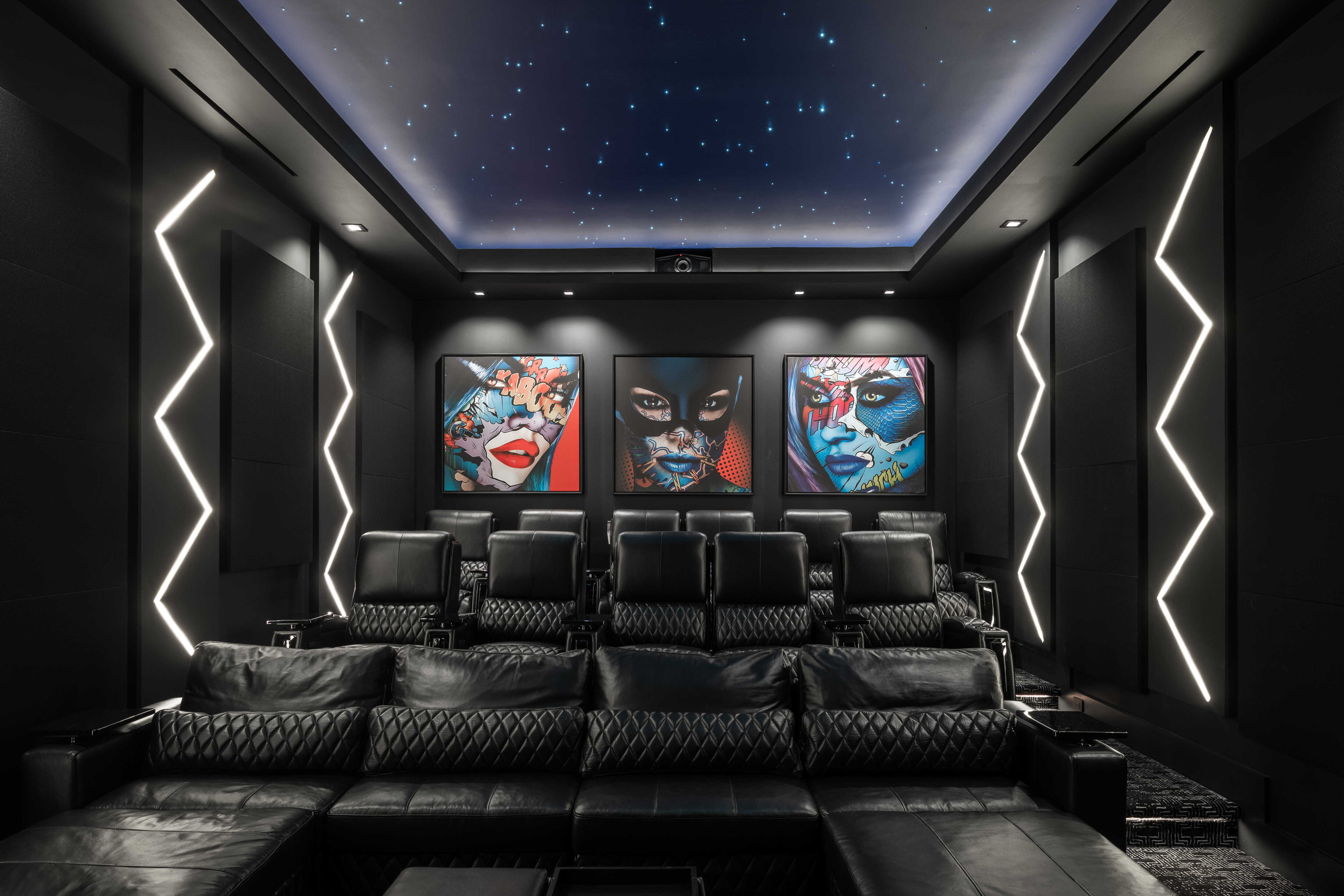 Luxury home theater with reclining leather seating, star-lit ceiling, acoustic wall panels, and bold contemporary artwork creating a dramatic cinematic experience inside a modern custom home in Memorial Houston.