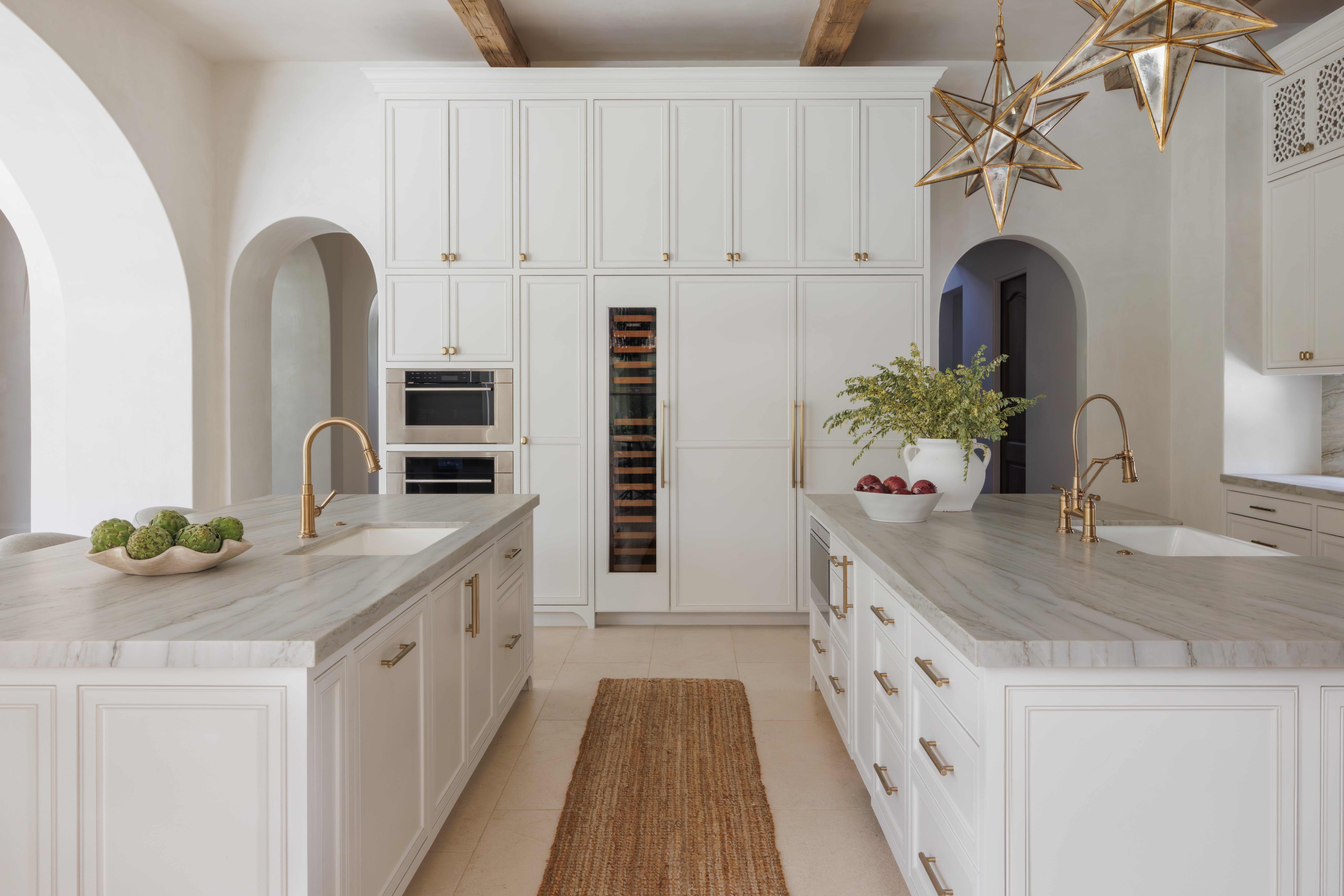Spanish Hacienda – Spacious double-island kitchen with marble surfaces, brass fixtures, tall custom cabinetry, and star-shaped pendant lighting.