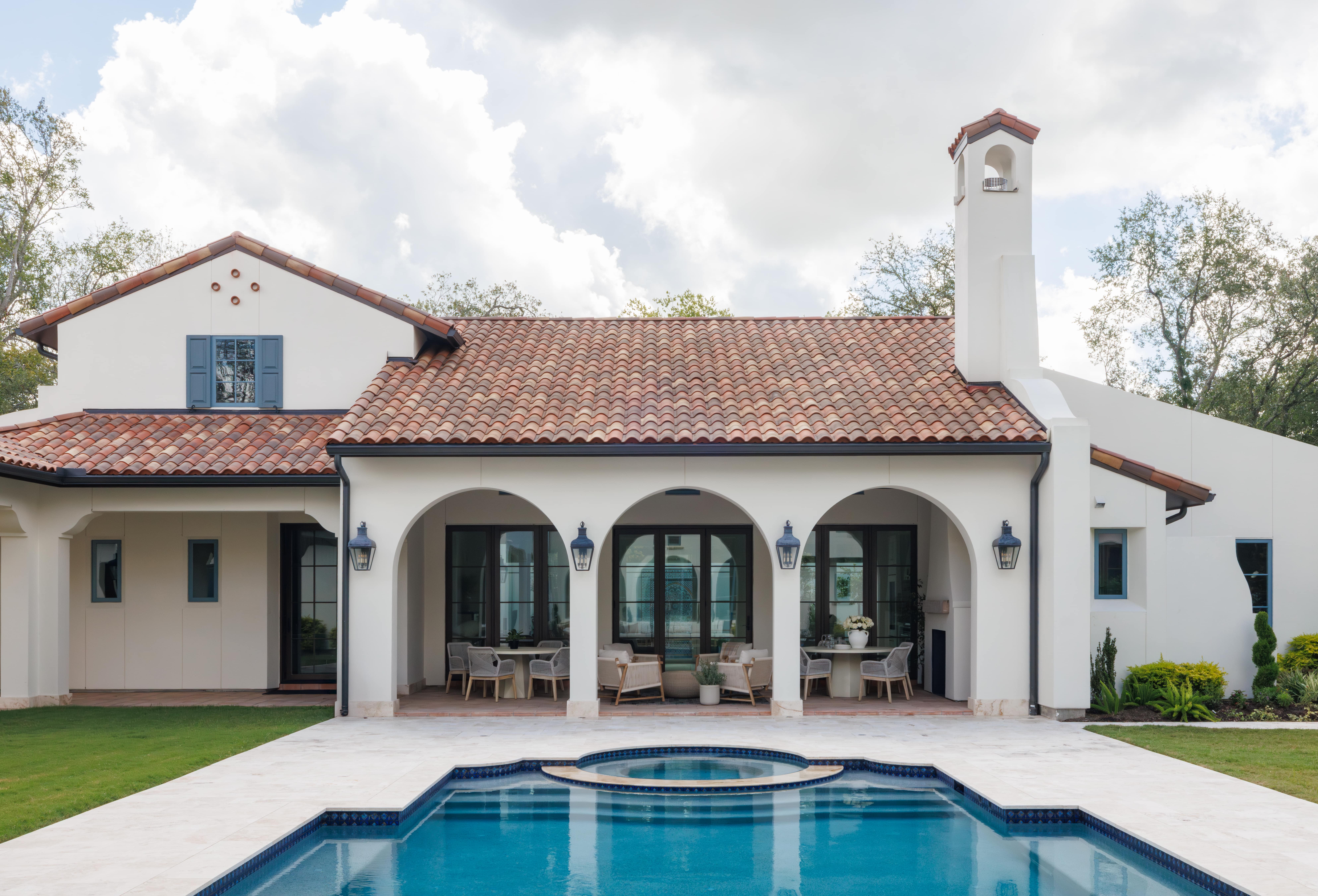 Spanish Hacienda – Rear exterior with arched loggia, clay tile roof, lantern lighting, and a serene pool with integrated spa.
