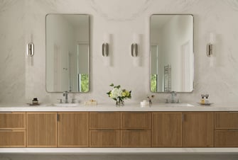 Bathroom with floating wood vanity, dual mirrors, marble walls, and modern sconces.