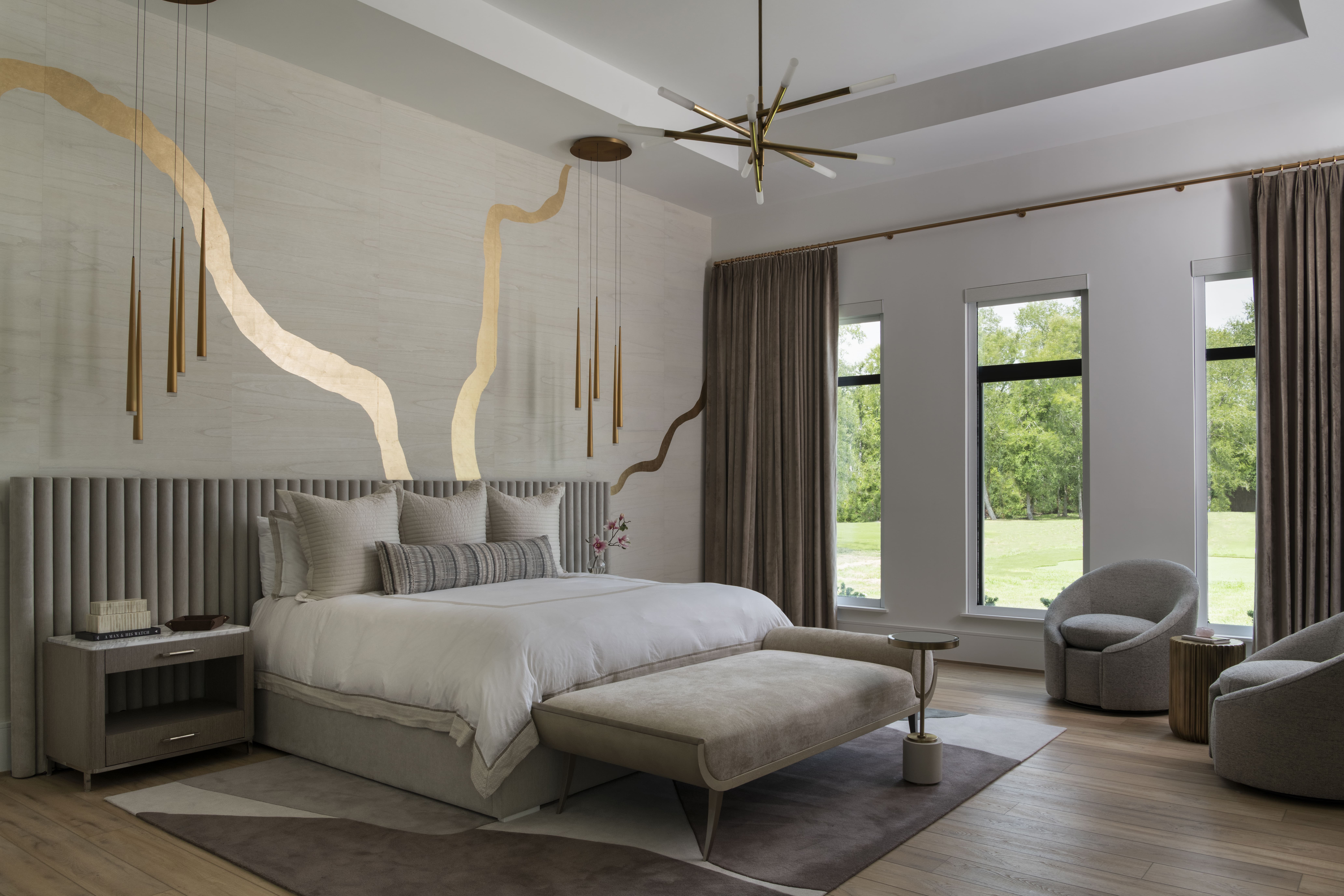 Primary bedroom featuring a sculptural gold accent wall, modern pendant lights, and soft neutral furnishings.
