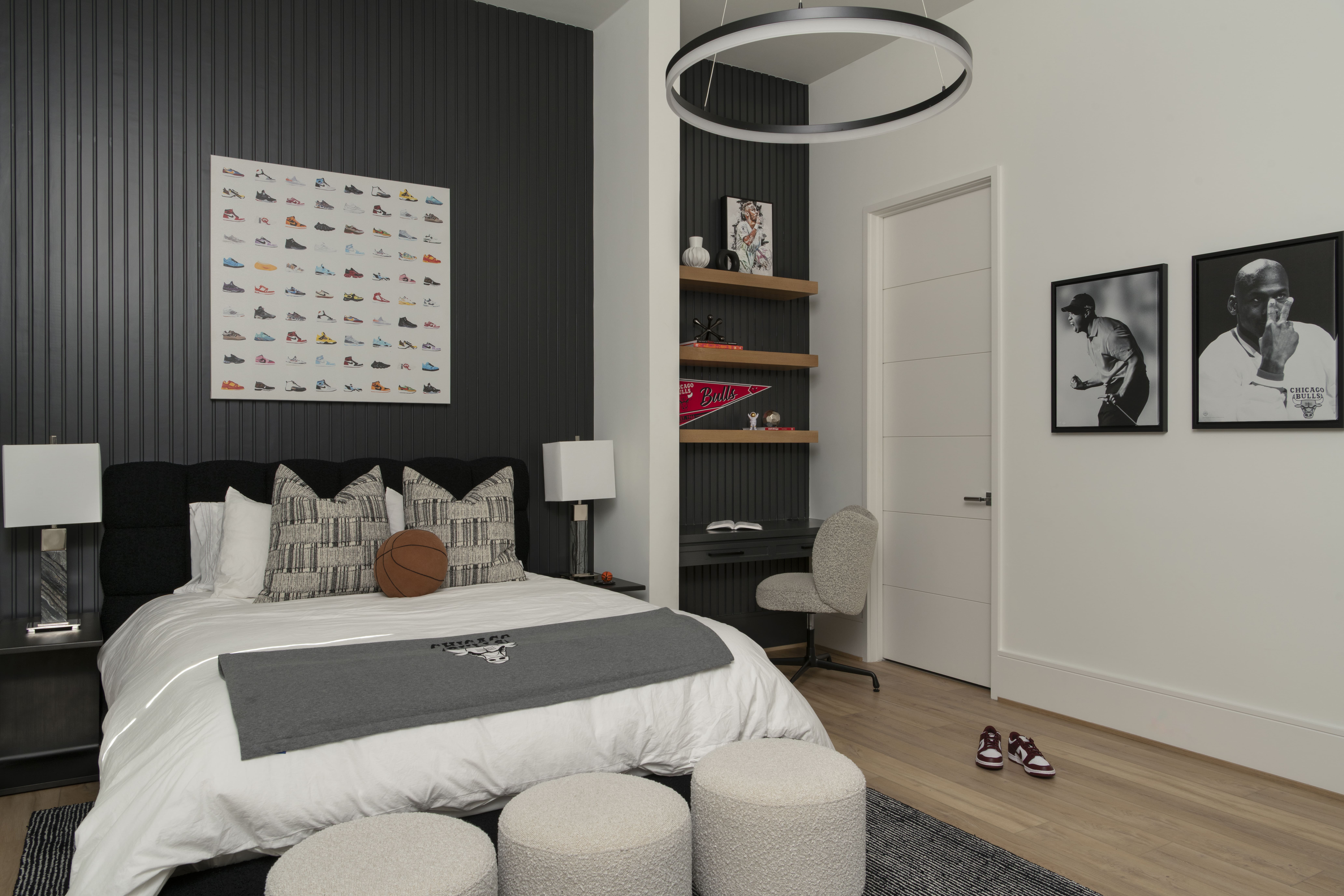 Bedroom with dark accent walls, modern bedding, sports-themed decor, and a built-in desk nook.