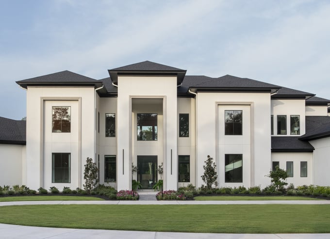 Front elevation of a modern transitional estate featuring white stucco exterior, black rooflines, symmetrical massing, tall recessed entry, and large-format windows, reflecting clean lines, intentional simplicity, and family-focused design.