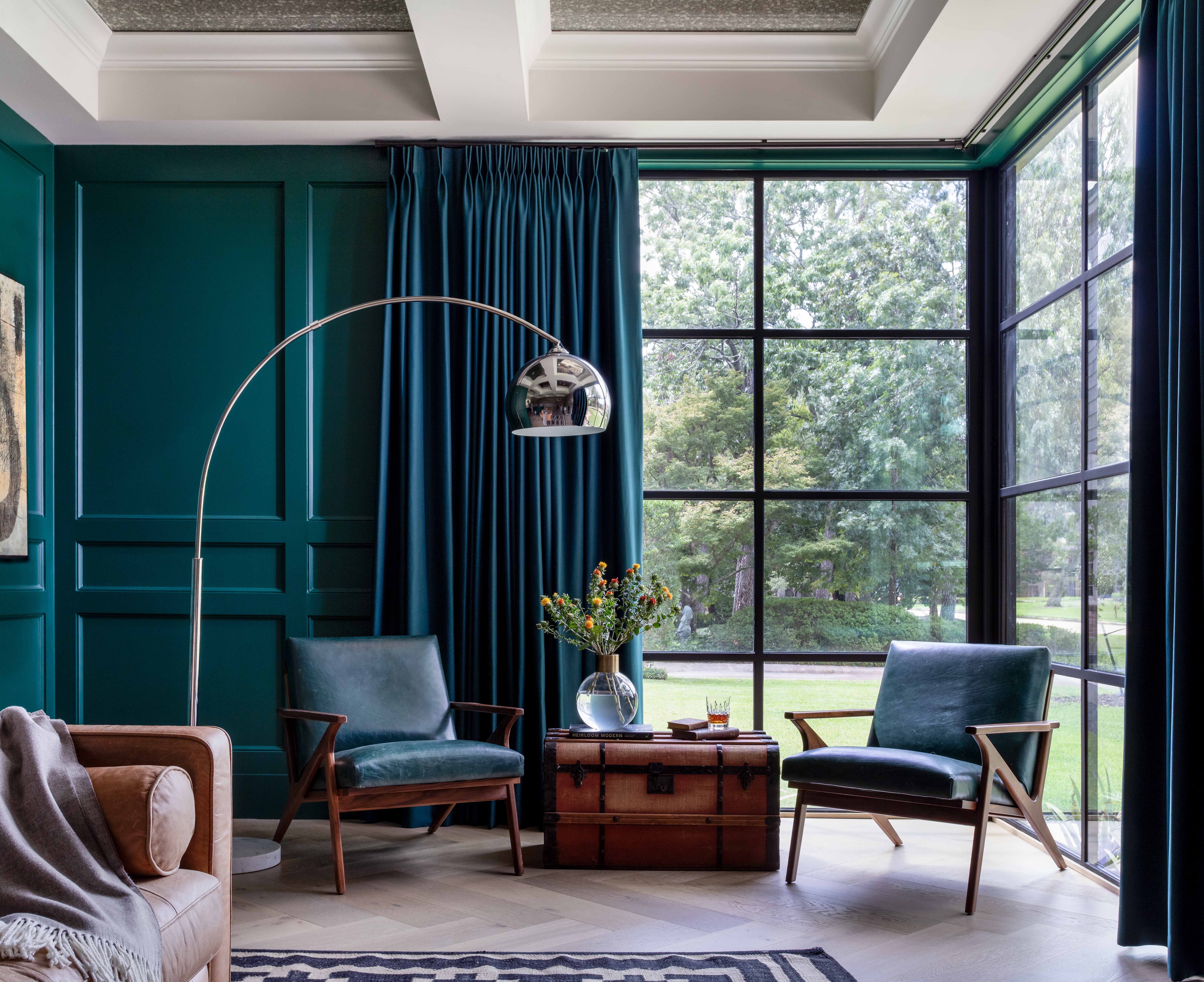 Expansive black-framed corner windows overlooking the landscape in a luxury sitting room.