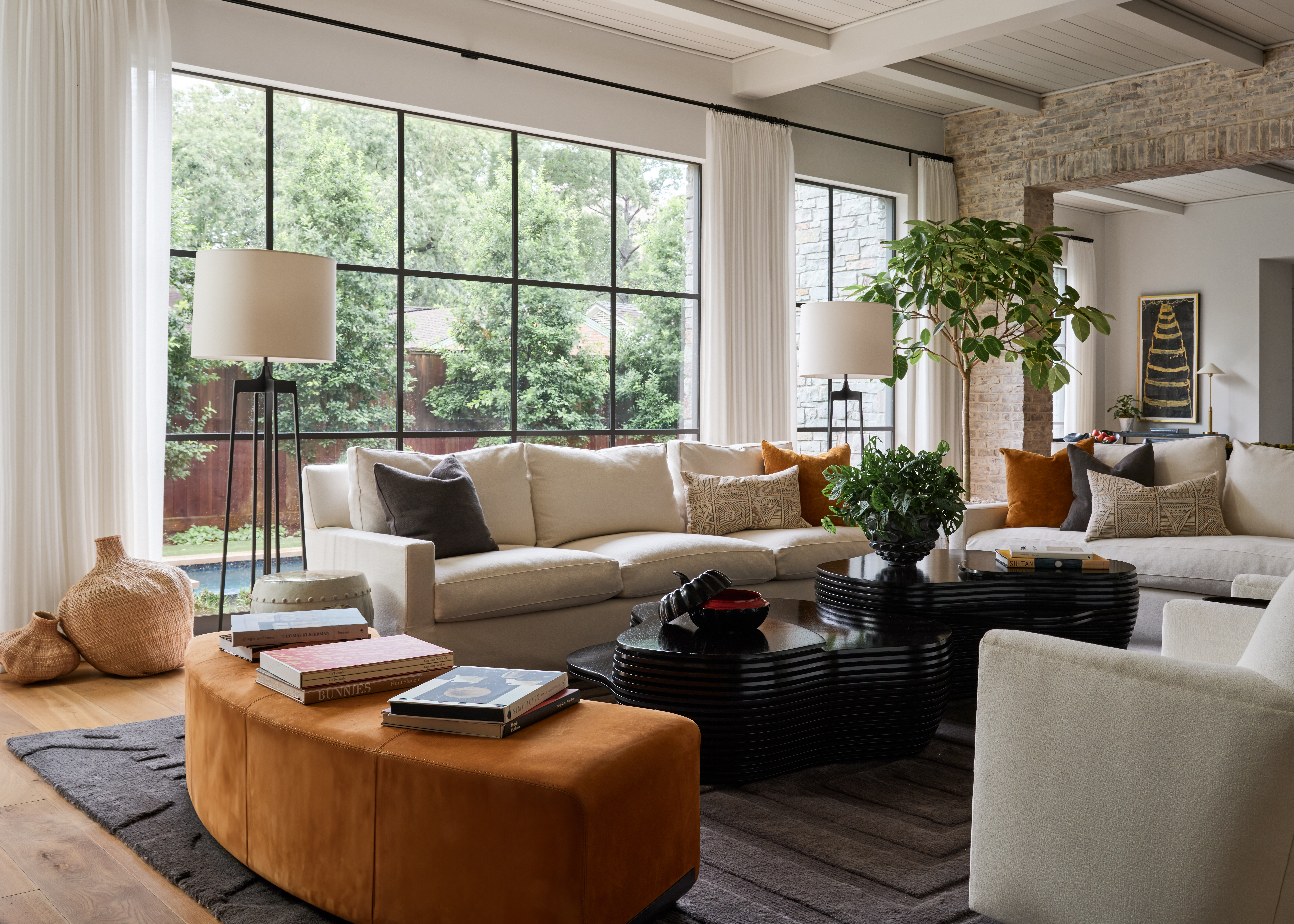 Large black-framed windows overlooking the yard and pool from a luxury custom home living room.