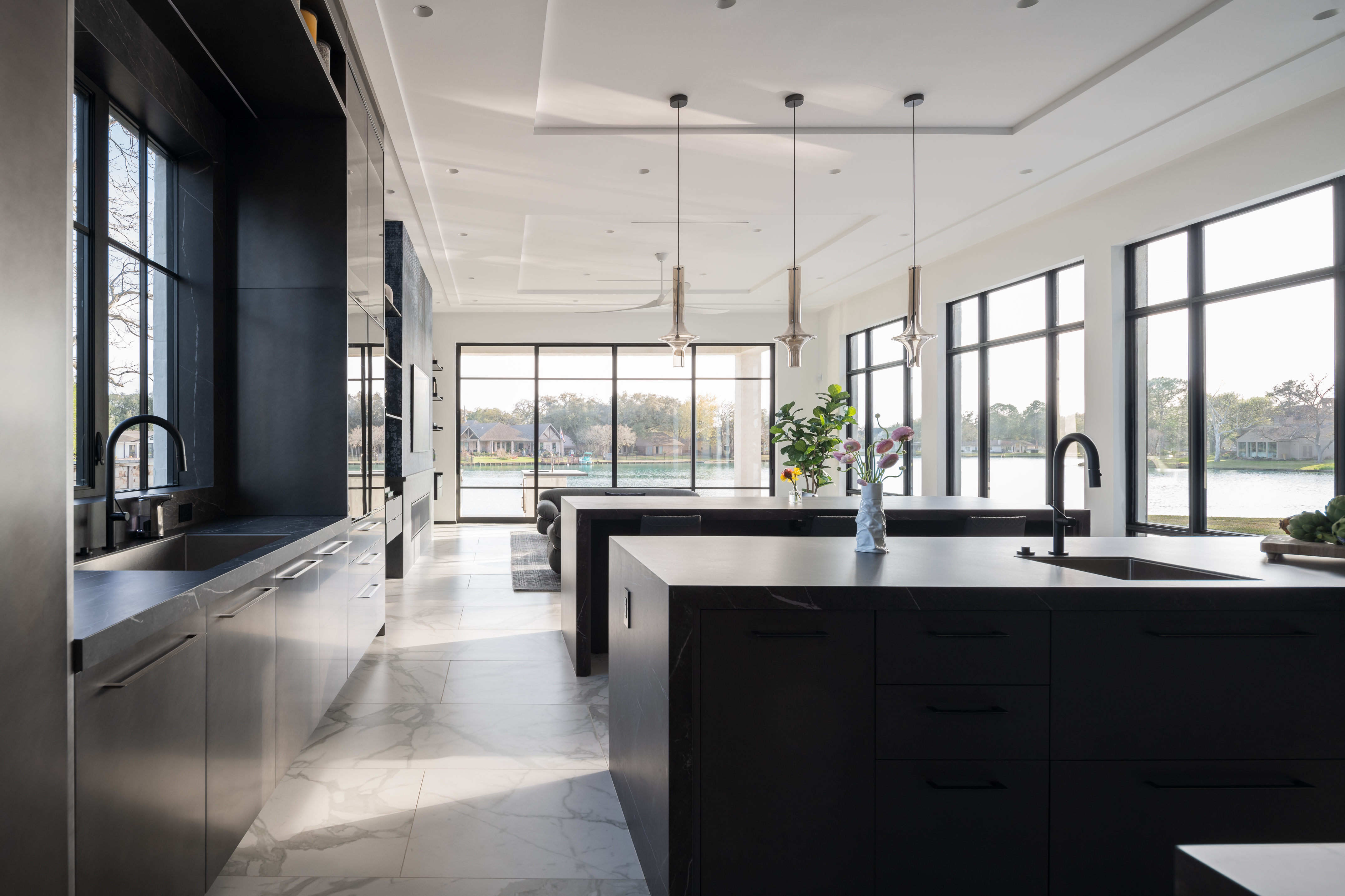 Floor-to-ceiling black-framed windows overlooking the water in a modern Houston custom home kitchen.